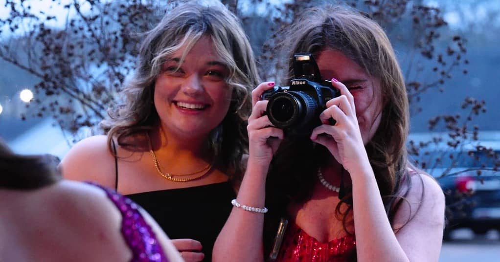 Two girls are taking a picture with a camera.